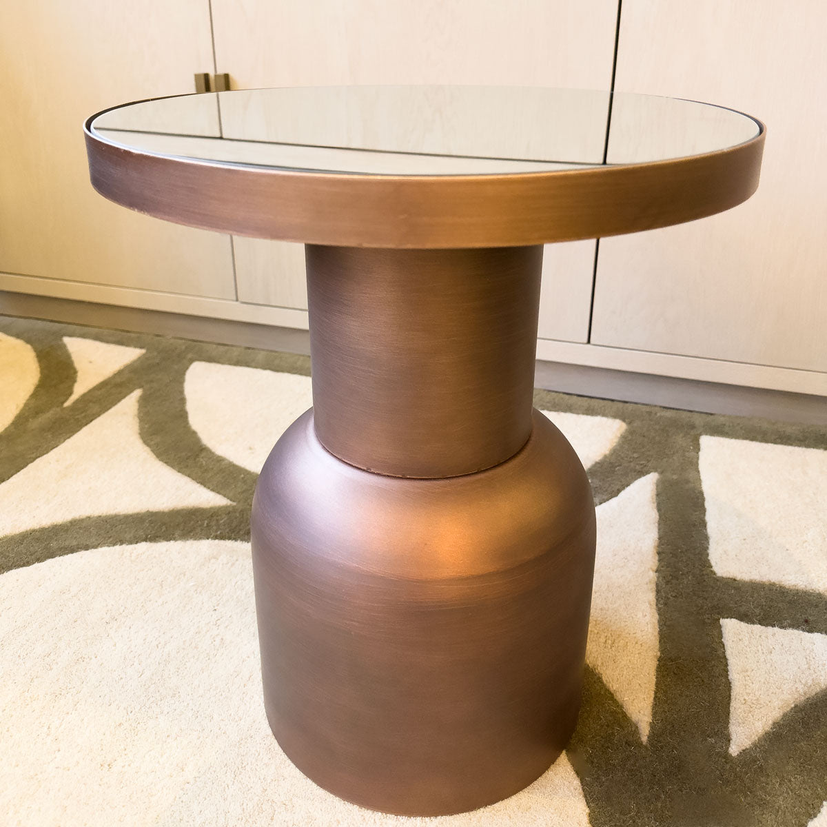 Bronze side table with glass top on a patterned rug