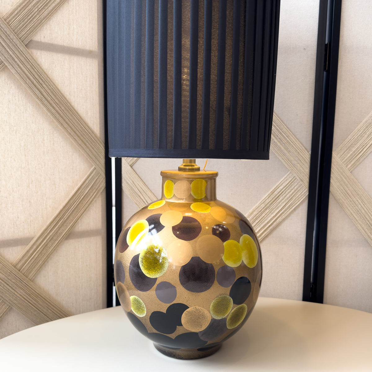 Decorative lamp with a patterned base and black shade on a surface.