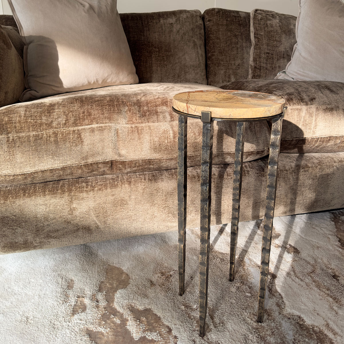 Small marble round table with metal legs in front of a brown sofa.