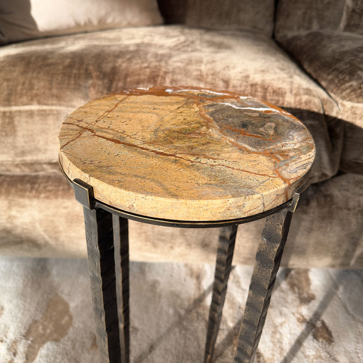Round stone table with metal legs on a textured surface