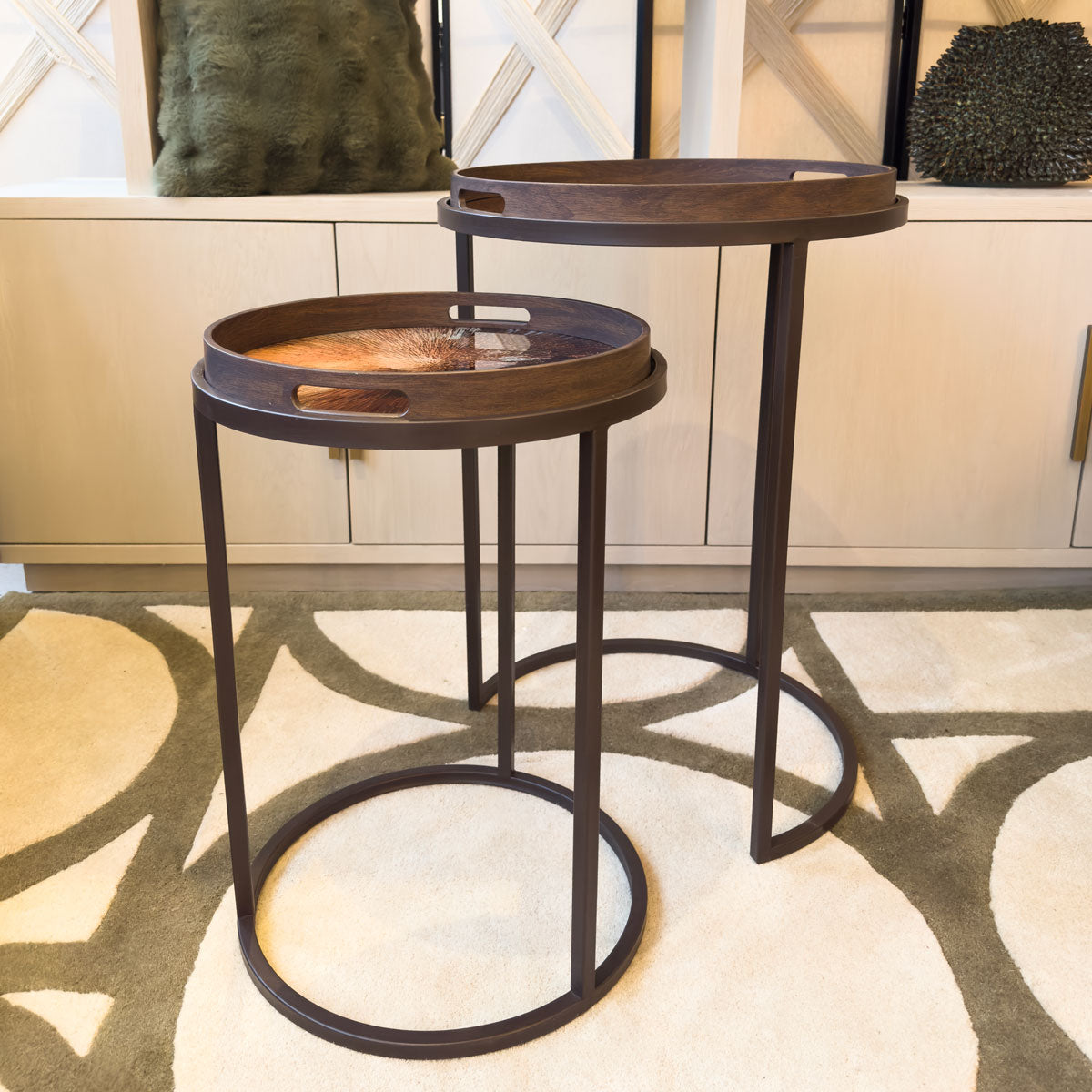 Two wooden tray tables with a rust coloured pattern, in a living room 