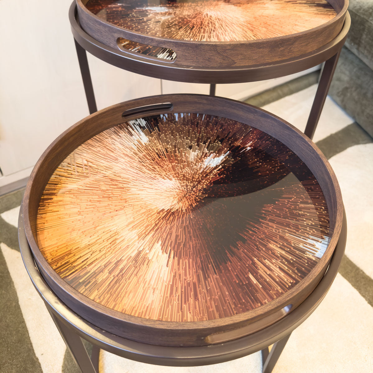 Two round wooden tables with decorative glass tops on a light-colored rug.