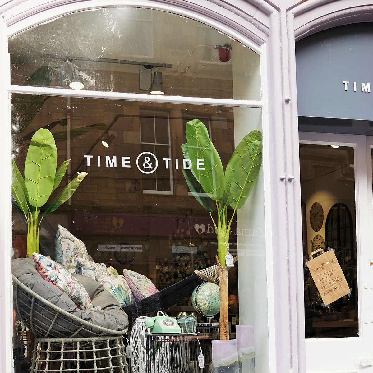 Storefront with 'Time & Tide' branding, interior visible through glass window.