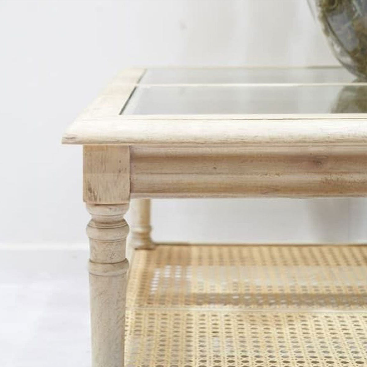 Light wooden coffee table with glass top and wicker shelf on a white background