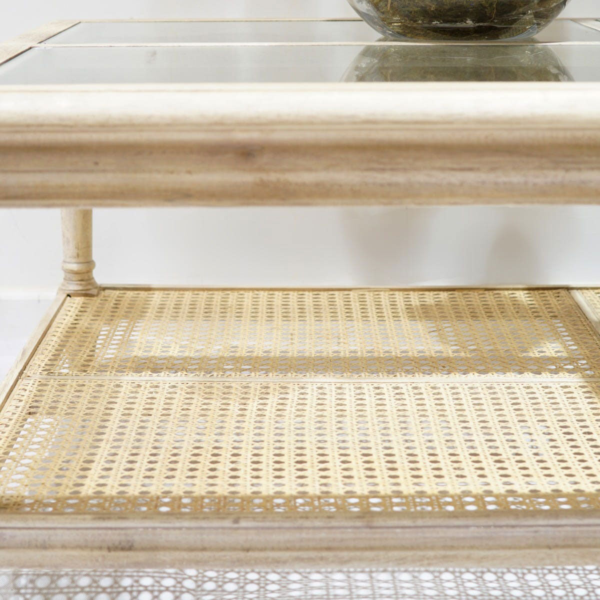 Two-tiered coffee table with woven bottom shelf and glass top.