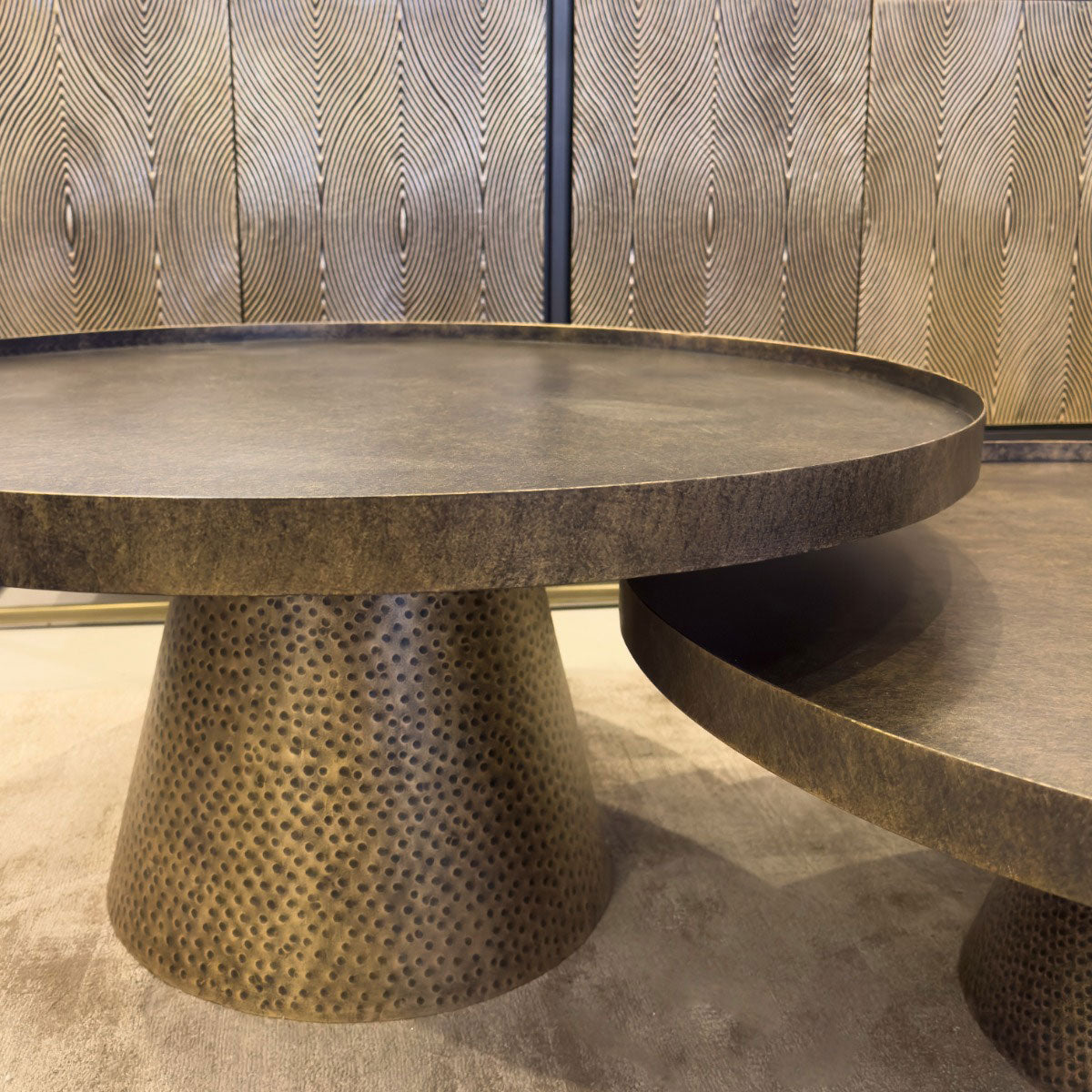 Round metal table with textured base against a patterned sideboard
