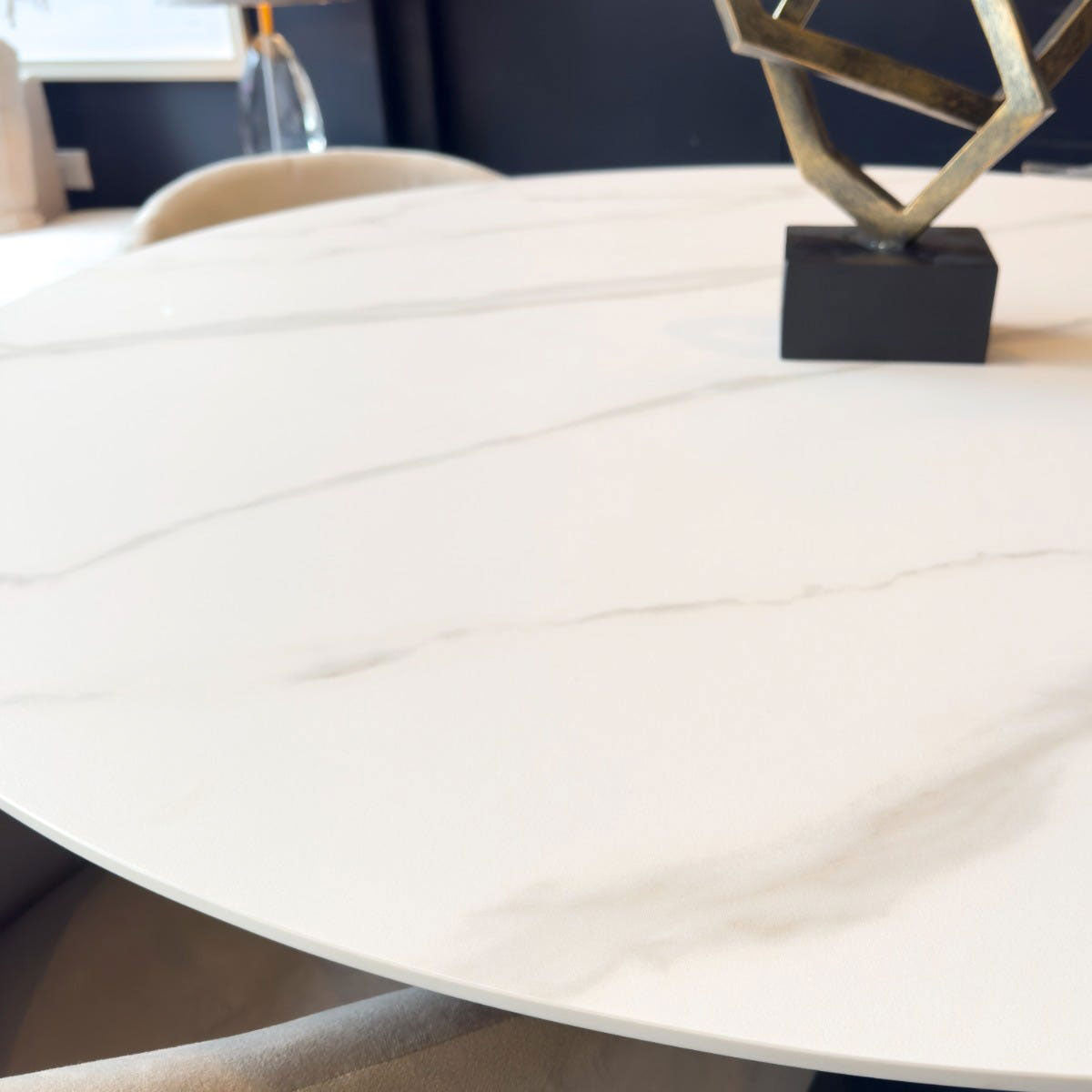 Round white marble table with a decorative metal sculpture.