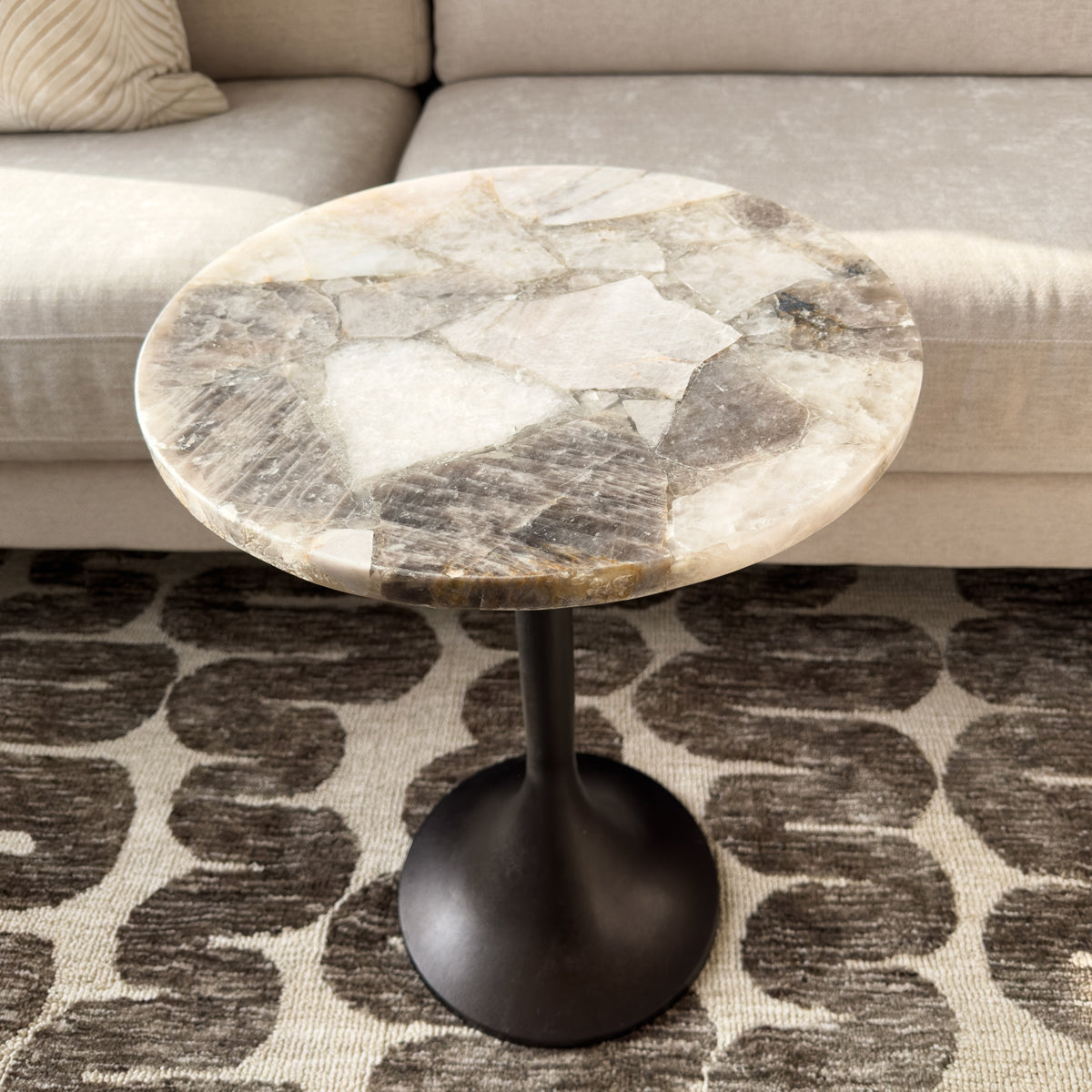 Round marble side table with a black base in a living room setting.