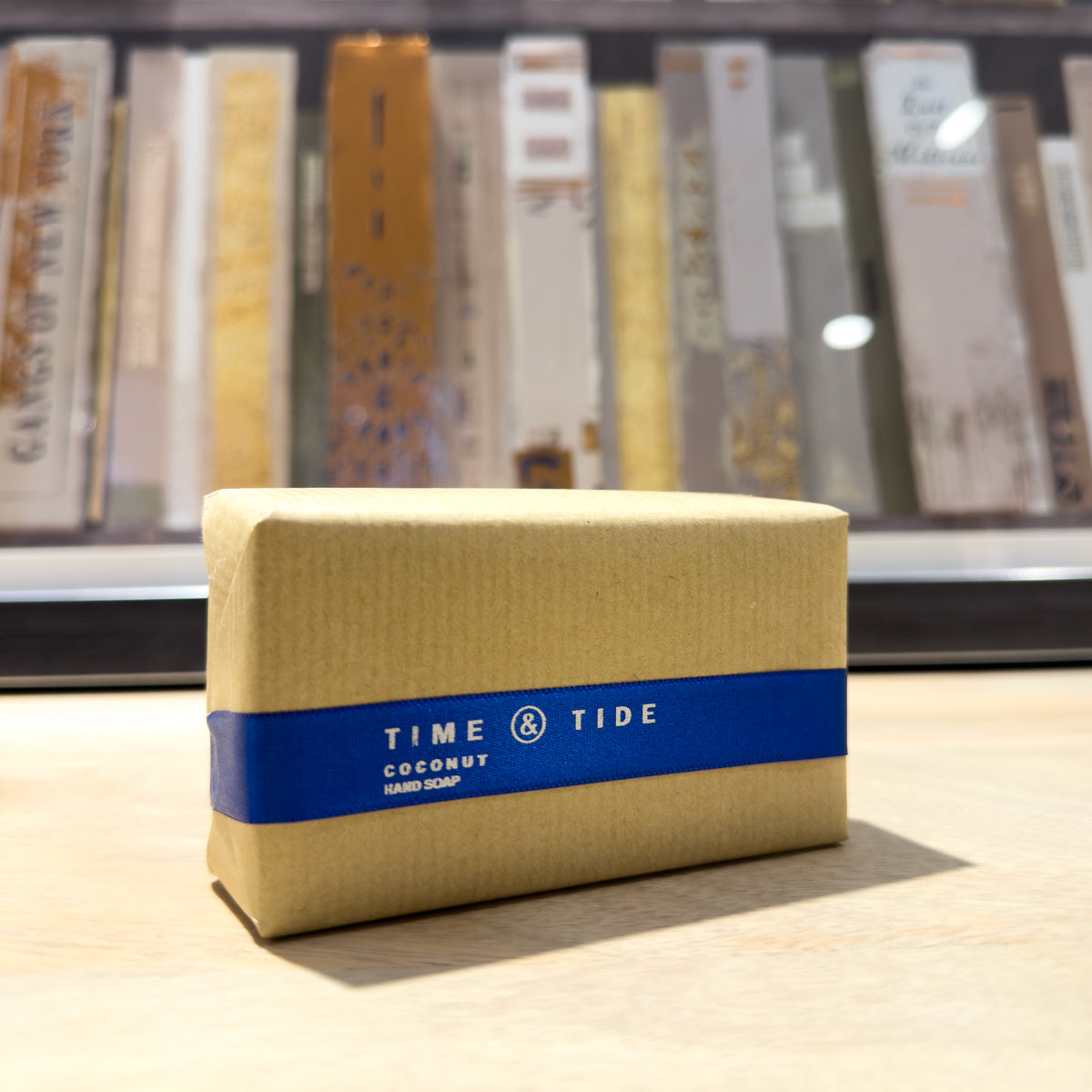 Beige coconut soap bar with blue label featuring 'Time & Tide' on a wooden surface.