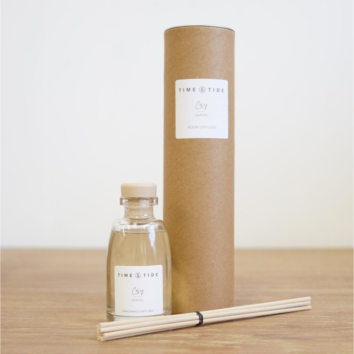A bottle and cardboard tube packaging with 'Time & Tide' labels on a wooden surface.