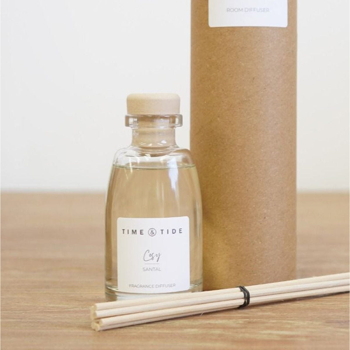 Clear glass diffuser bottle with wooden sticks and 'Time & Tide' label on a wooden surface.