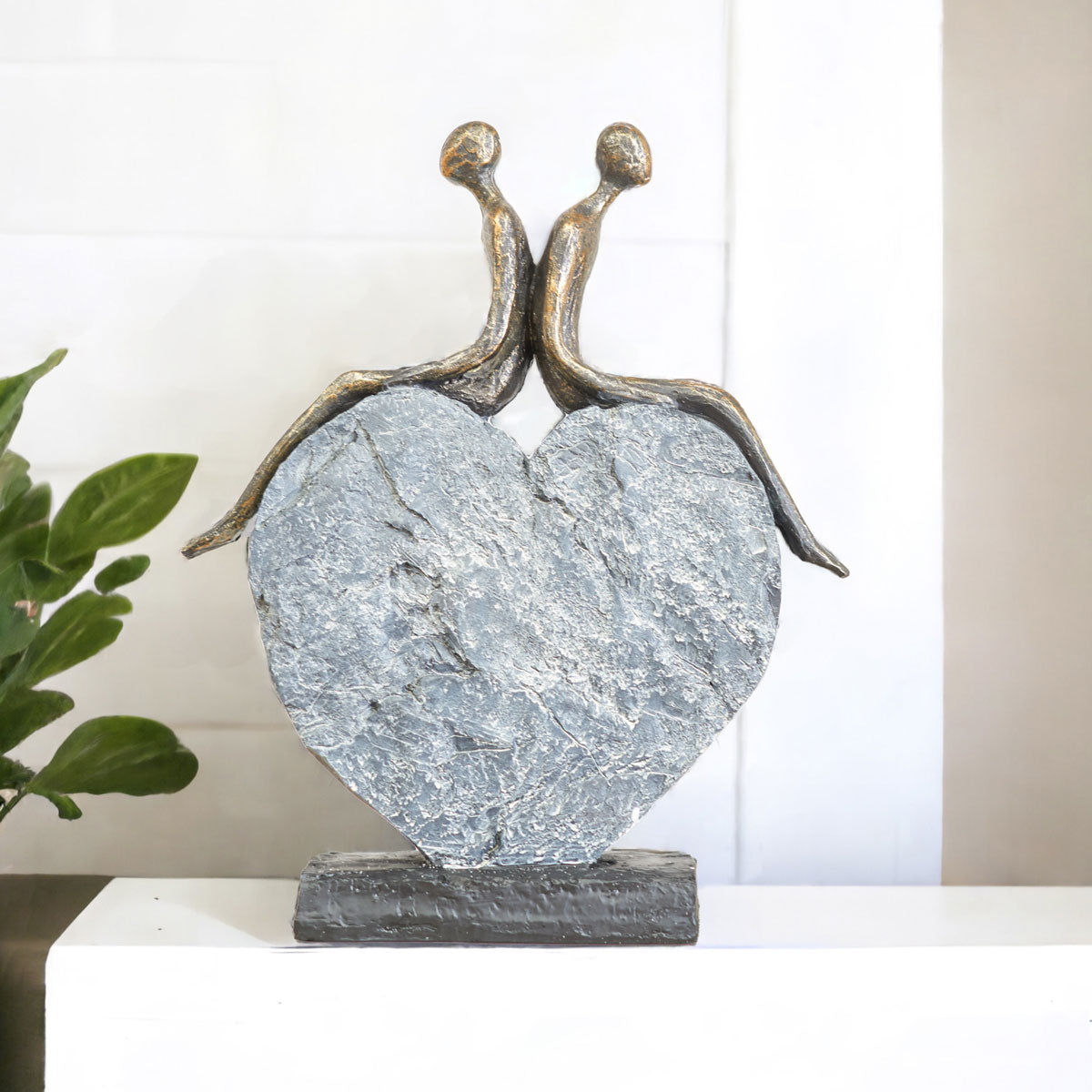Bronze sculpture of two people embracing on a heart-shaped stone base.