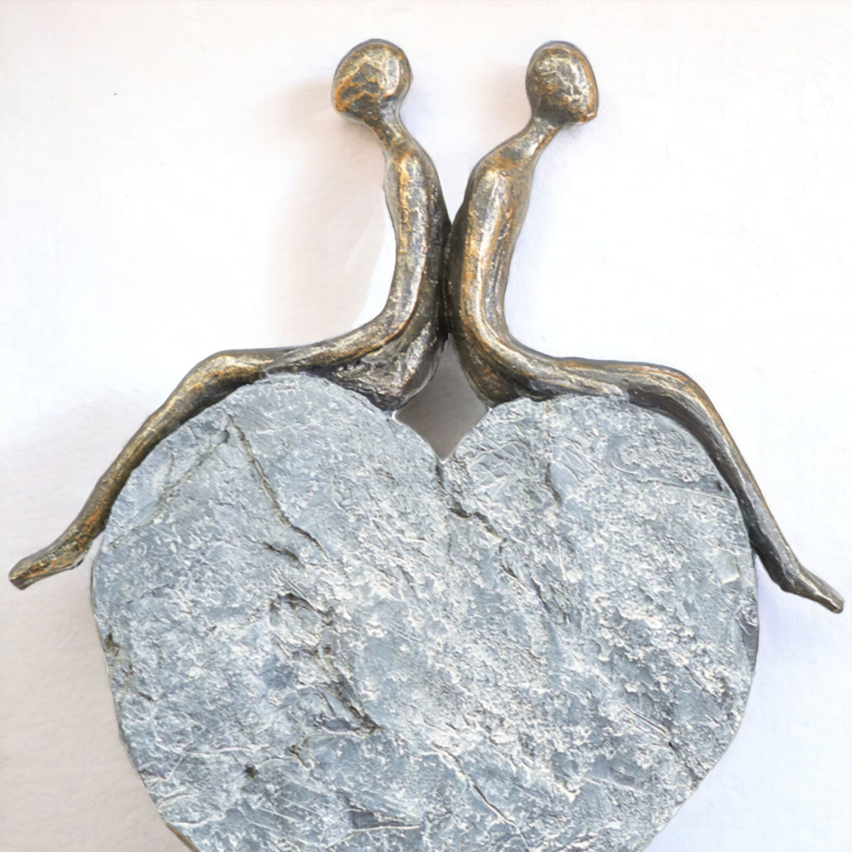 Bronze sculpture of two people holding hands on a stone base