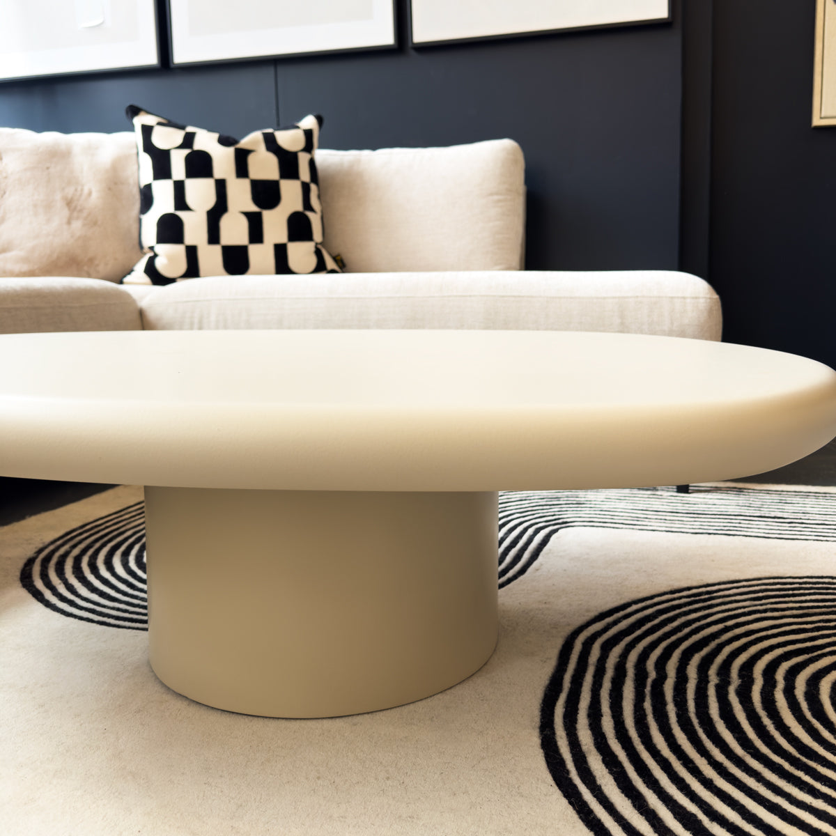Beige coffee table in a living room with a checkered pillow on a beige sofa.