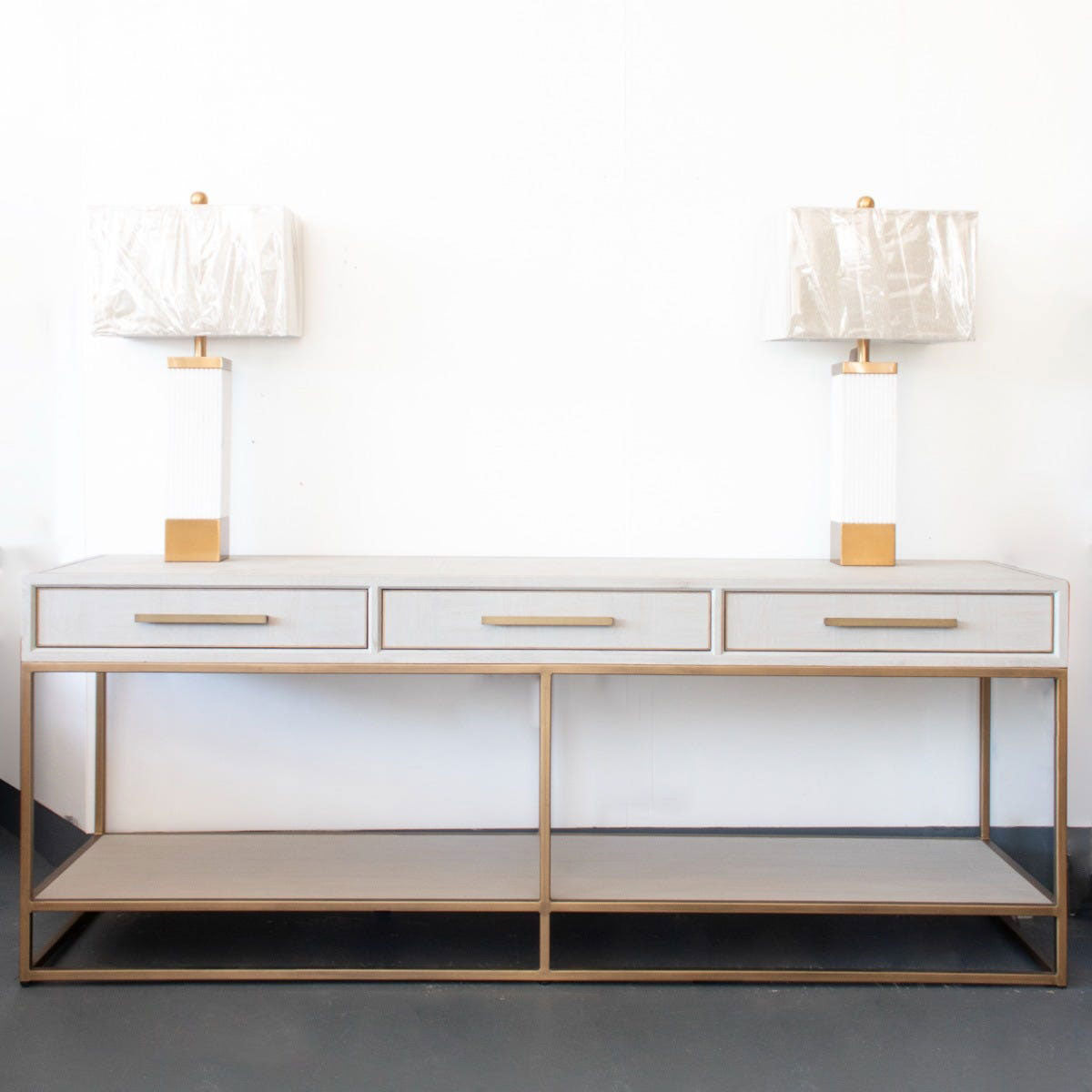Cream parquet console table with two lamps on a white background