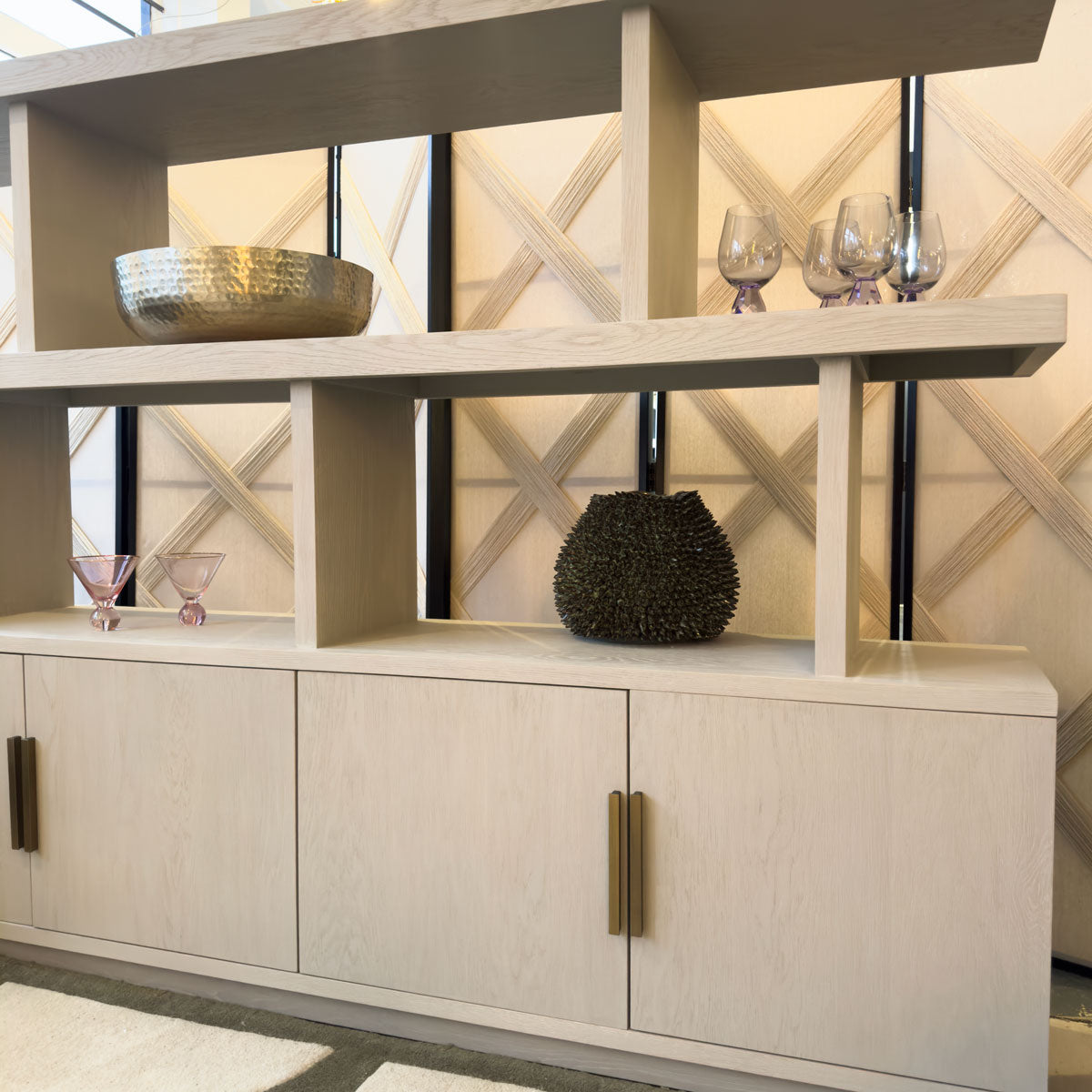 Modern interior design with a light wood shelf unit with doors against a decorative wall.