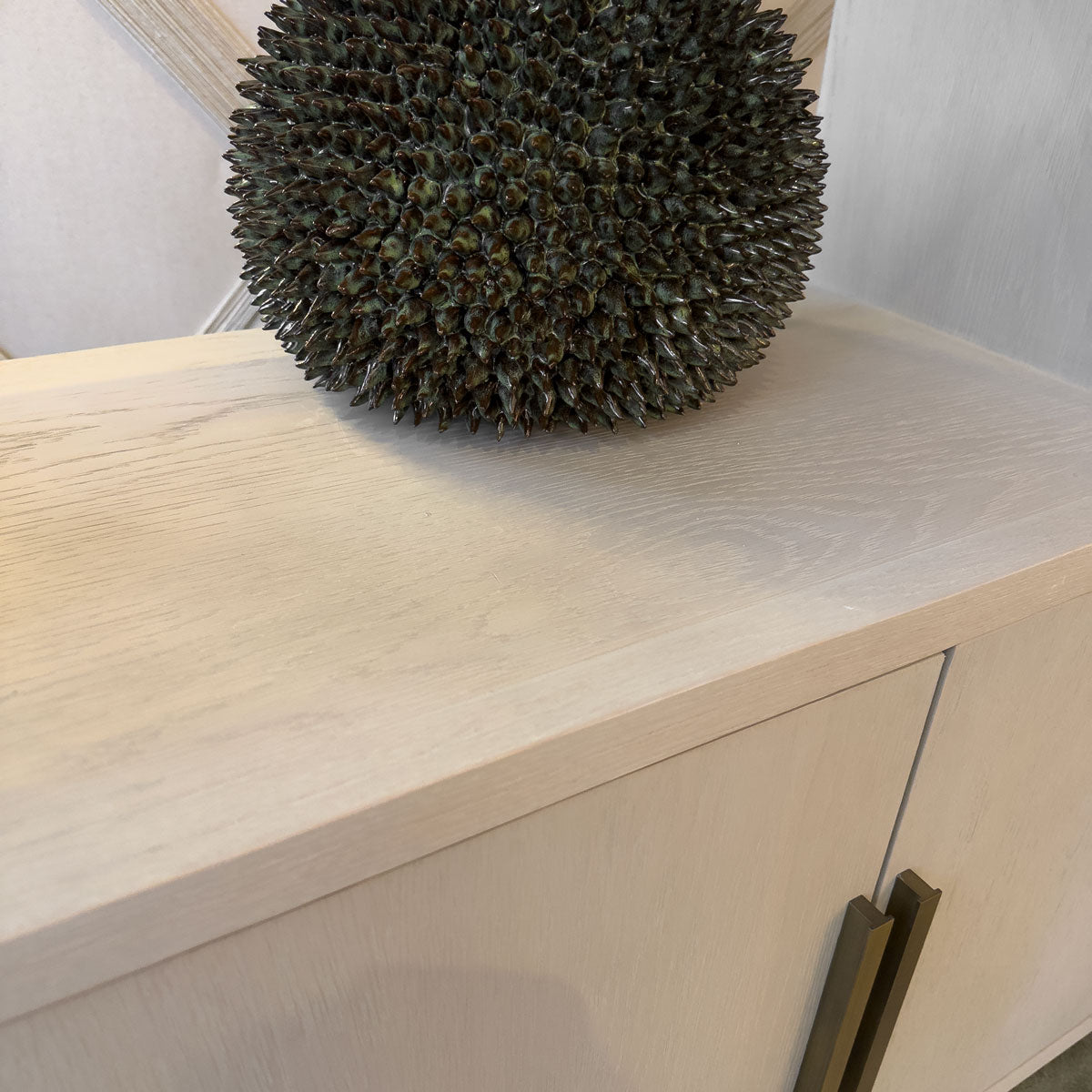 Spiky green fruit shaped vase on a pale wooden surface