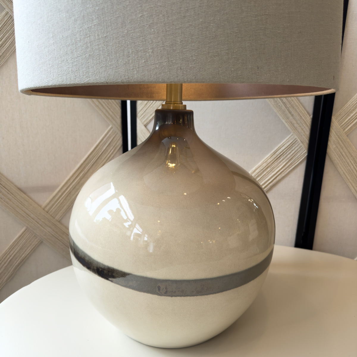 Table lamp with a beige ceramic base and gray shade on a white surface.