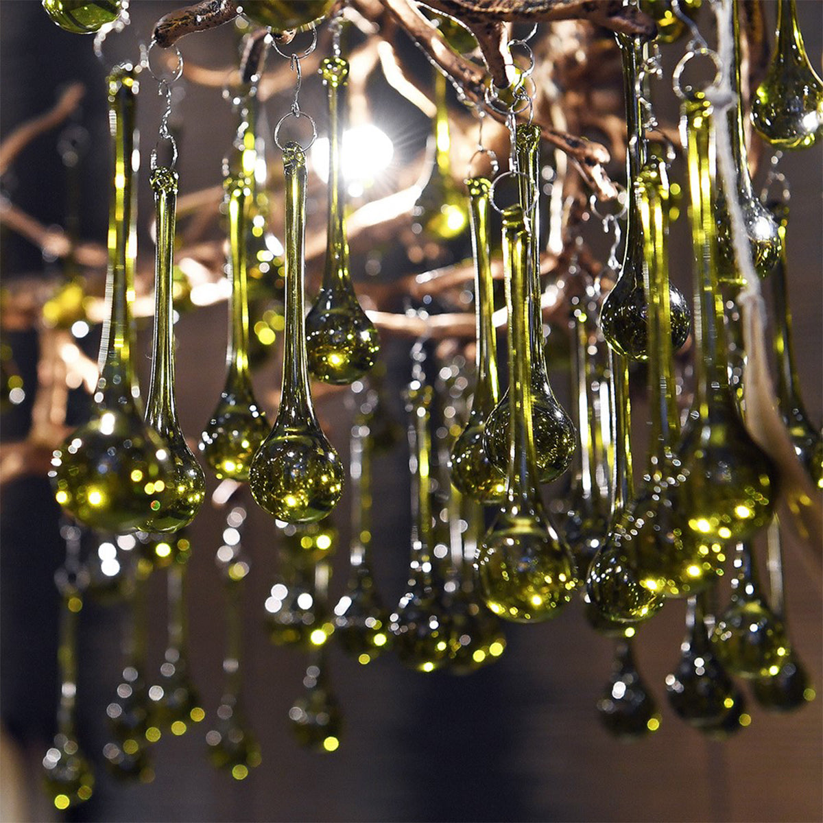 A green chandelier hanging with glass droplet designs on a blurred background