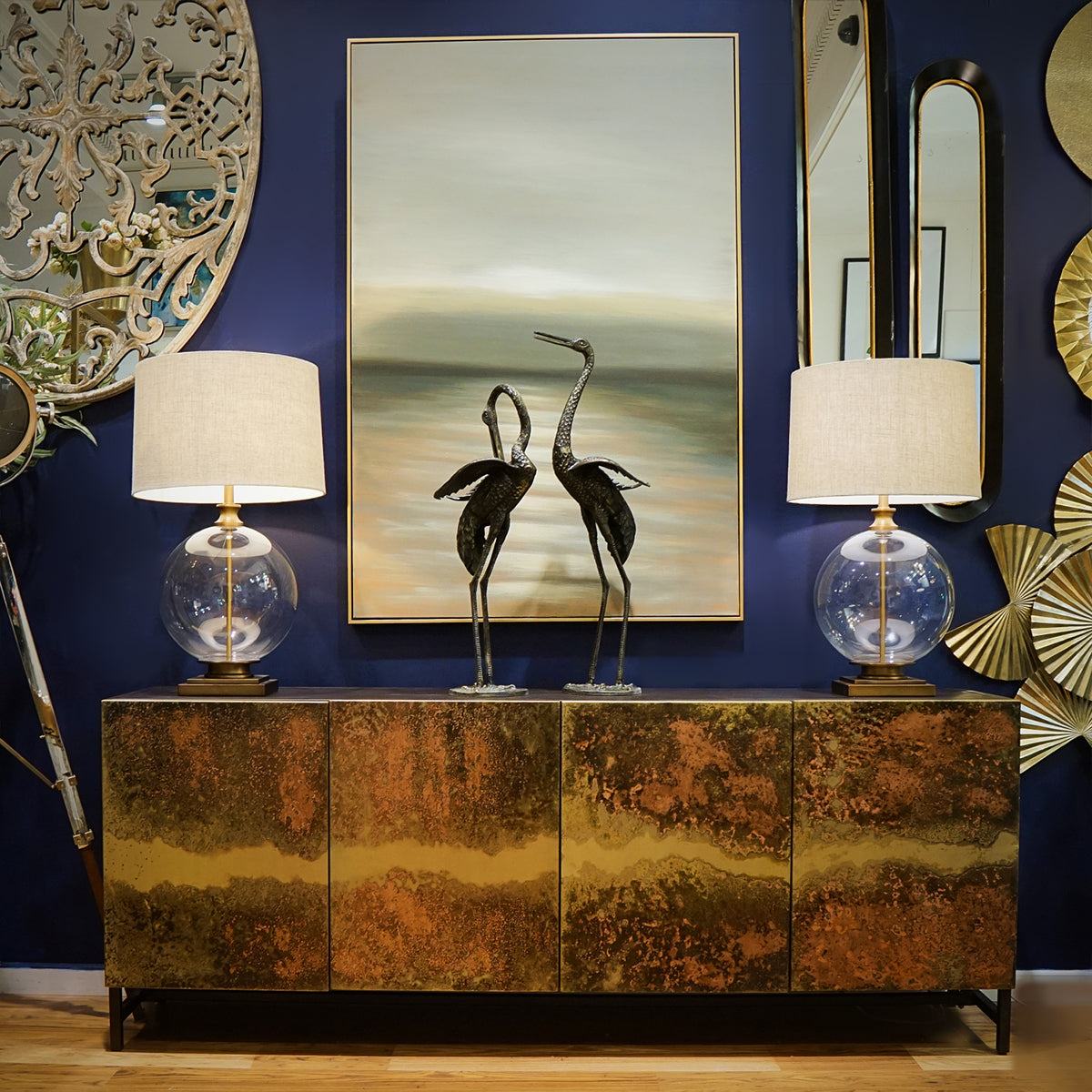 Decorative room interior with a metallic sidebaord, lamps, and wall art.