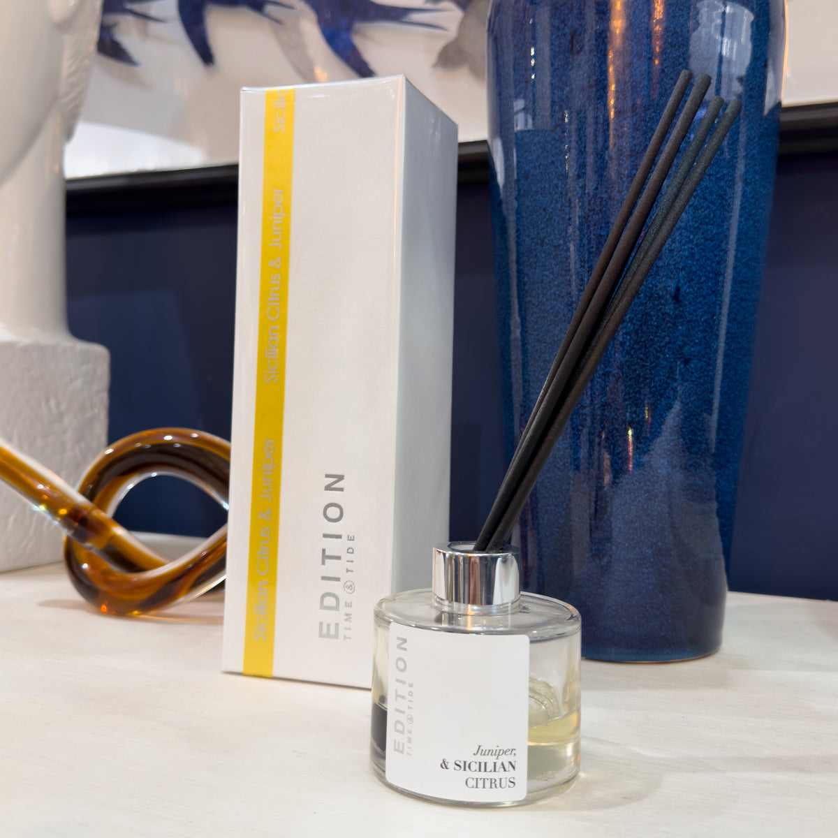 Diffuser bottle with black reeds and packaging on a surface