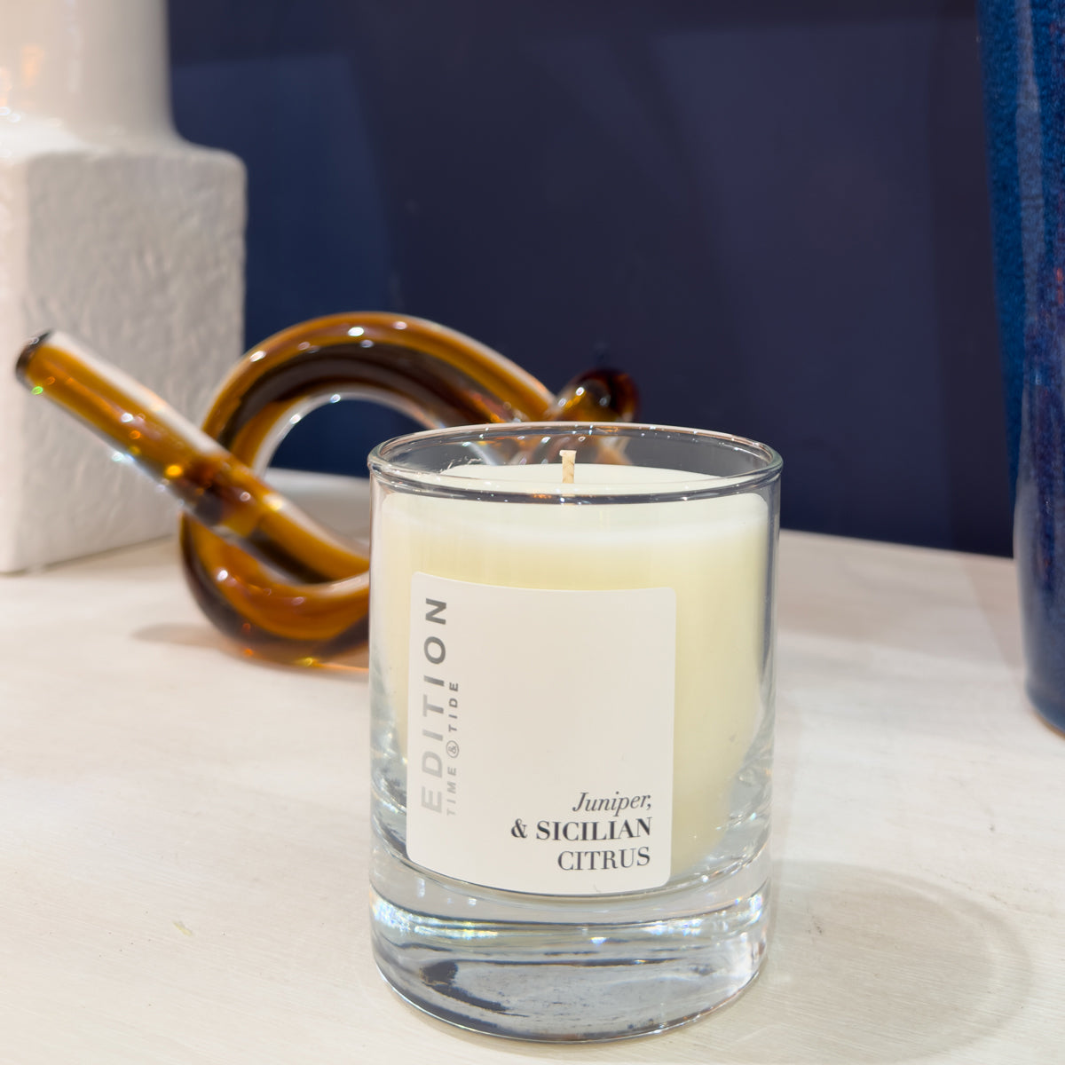 Candle in a glass container with a label on a surface