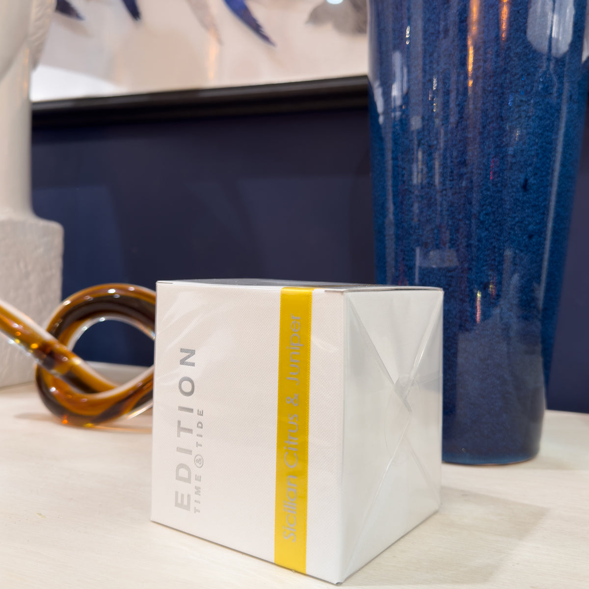 White box with a yellow stripe featuring 'Edition' branding on a surface with decorative items.
