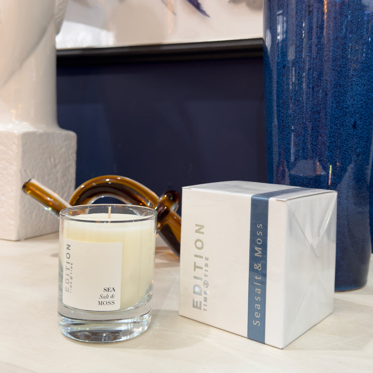Candle with a 'Edition' box on a white console table