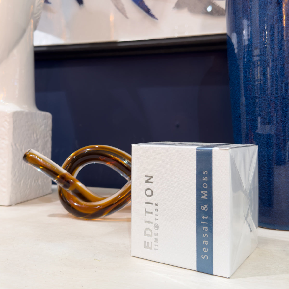 Decorative orange glass knot with a box labeled 'Edition Seasalt & Moss' on a surface.