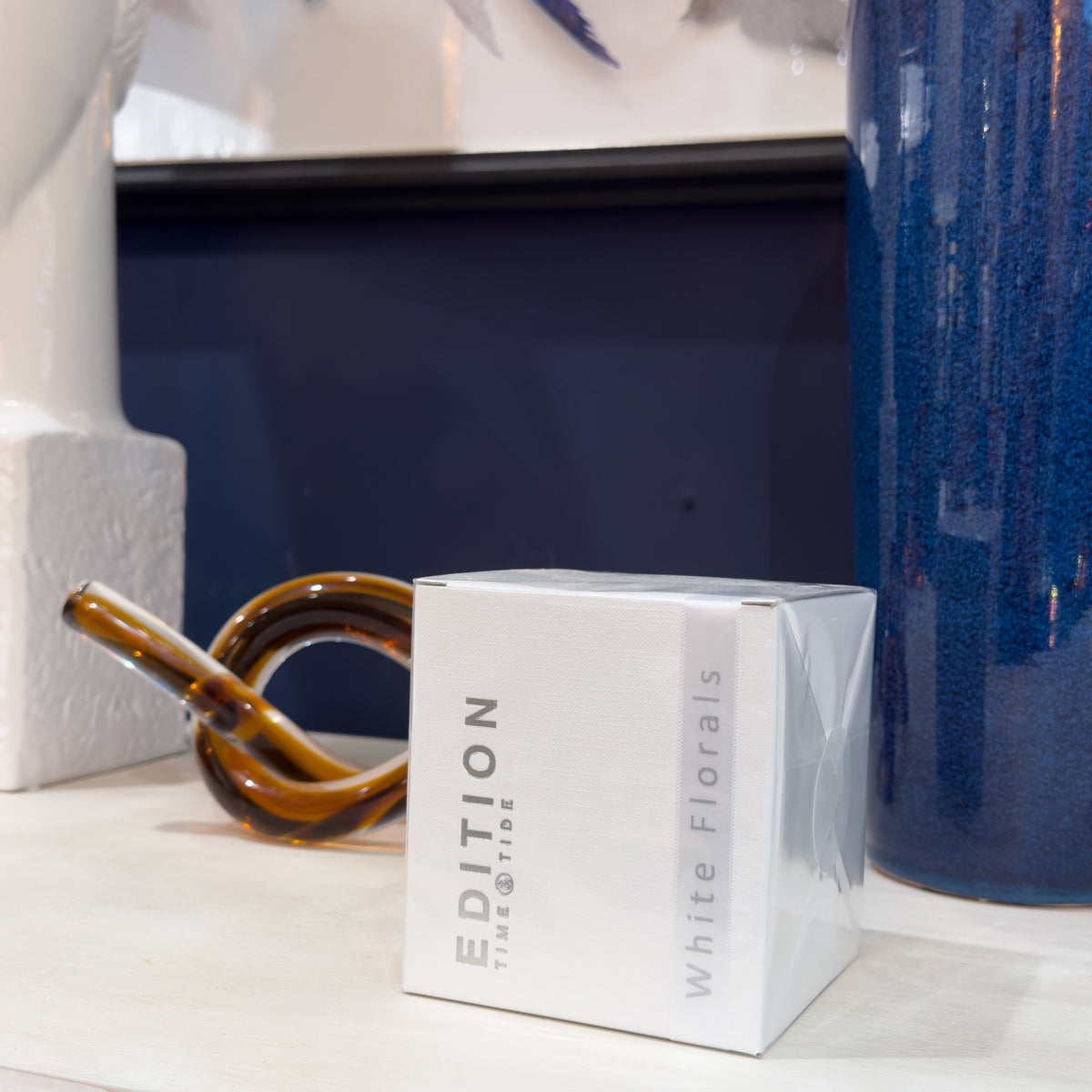 White box labeled 'Edition' with 'White Florals' text on a shelf with decorative items.