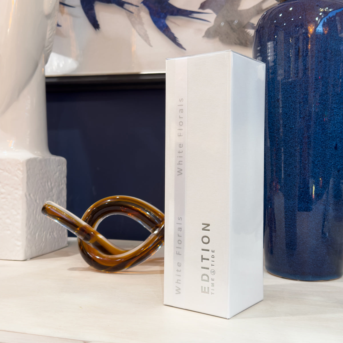 White decorative box with 'Edition' branding on a surface with artistic background