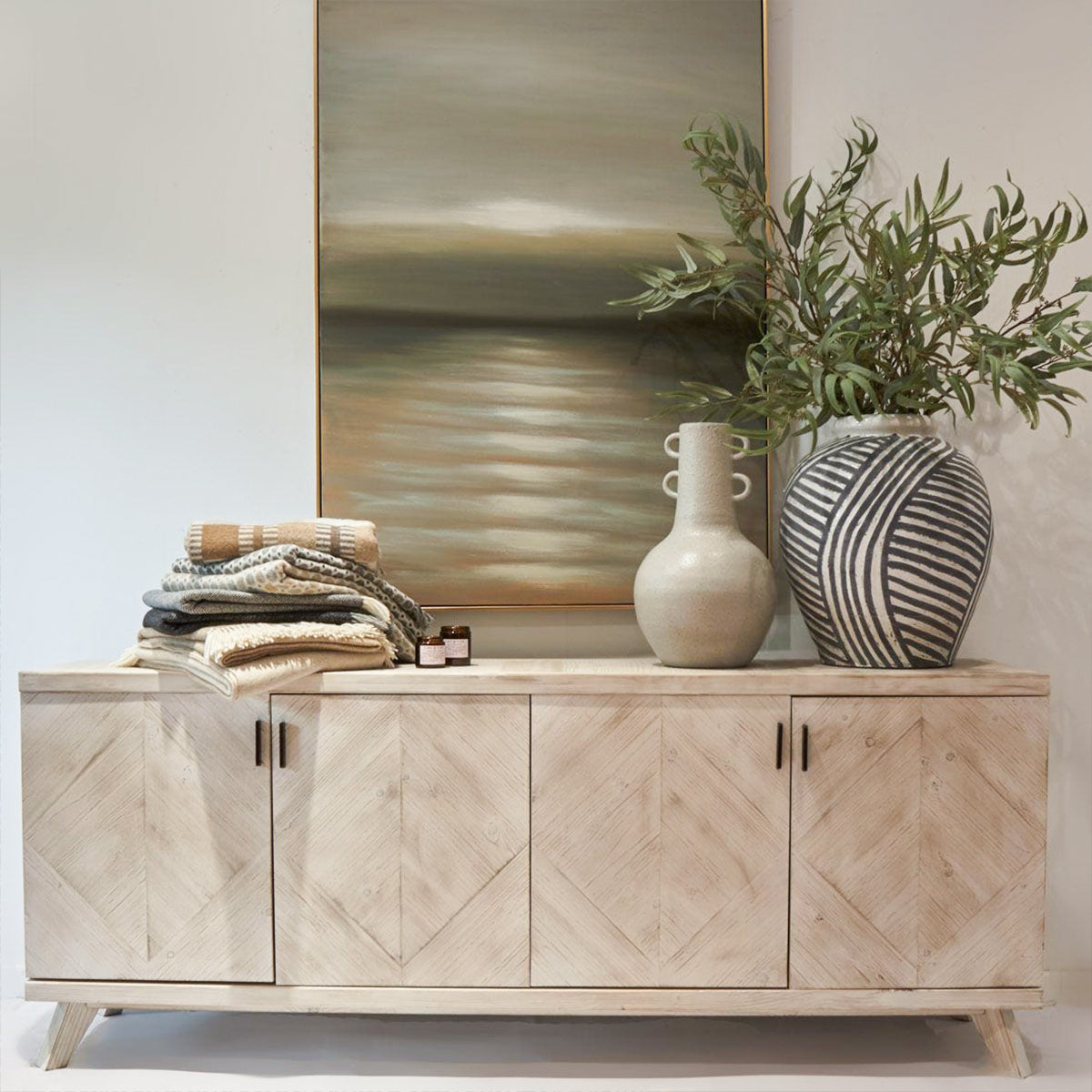 Wooden sideboard with decorative items including a mirror, vases, and plants.