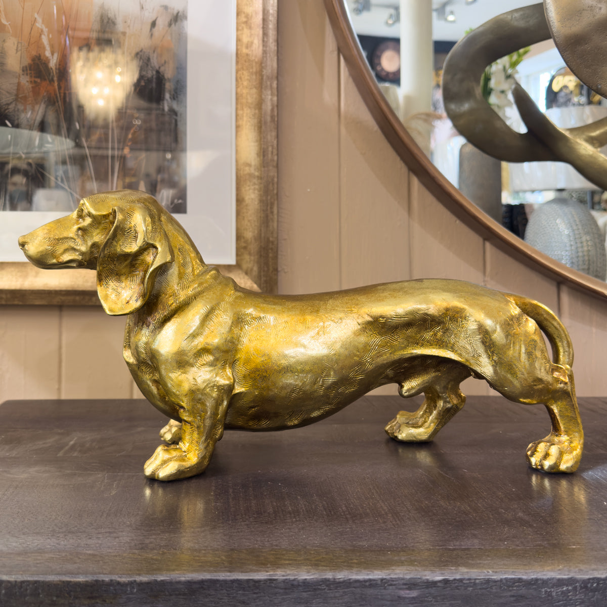 Gold dog ornament on a dark surface with a mirror in the background