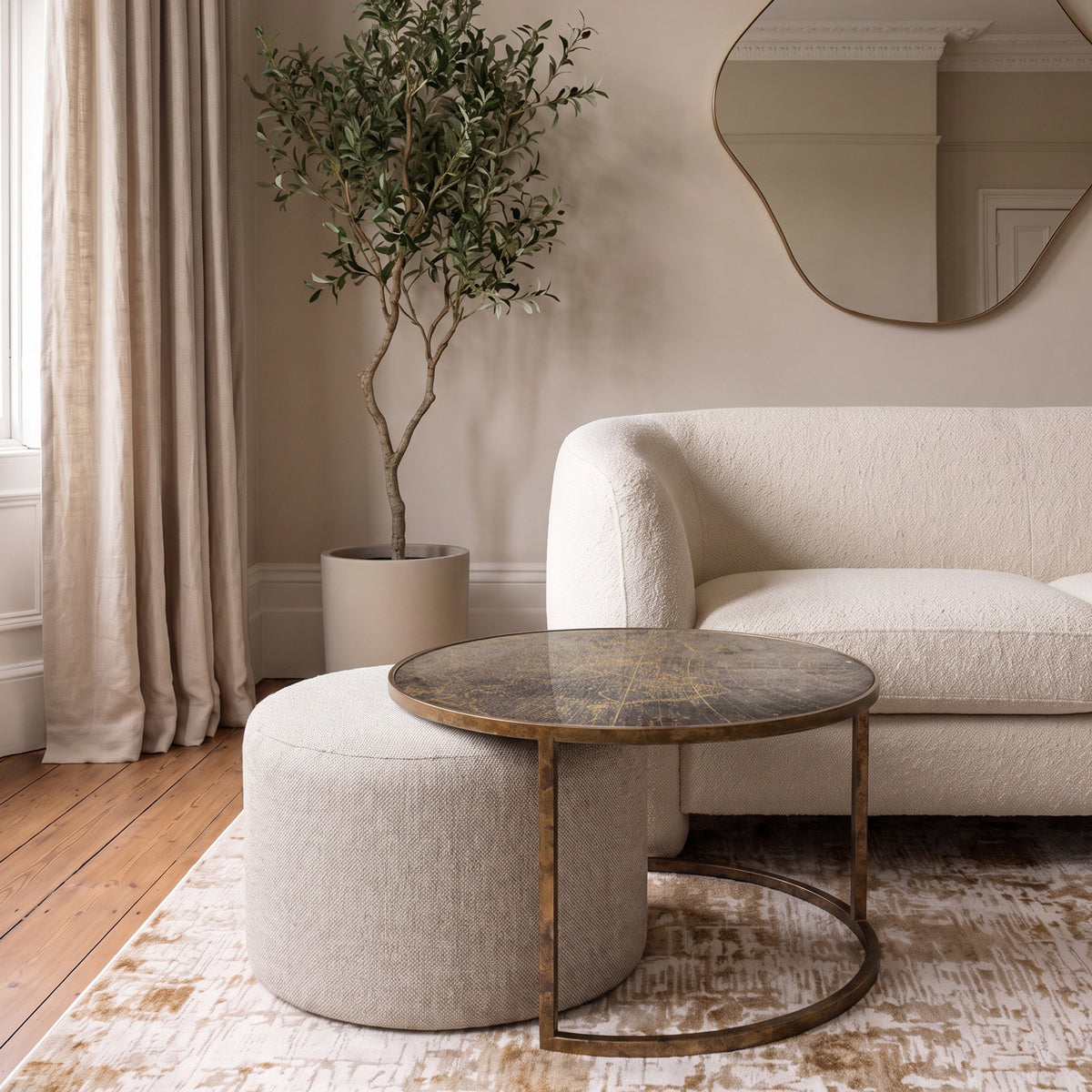 A map coffee table with a distressed world map motif top and gold metal frame, paired with a matching cylindrical upholstered ottoman in a styled living room setting.