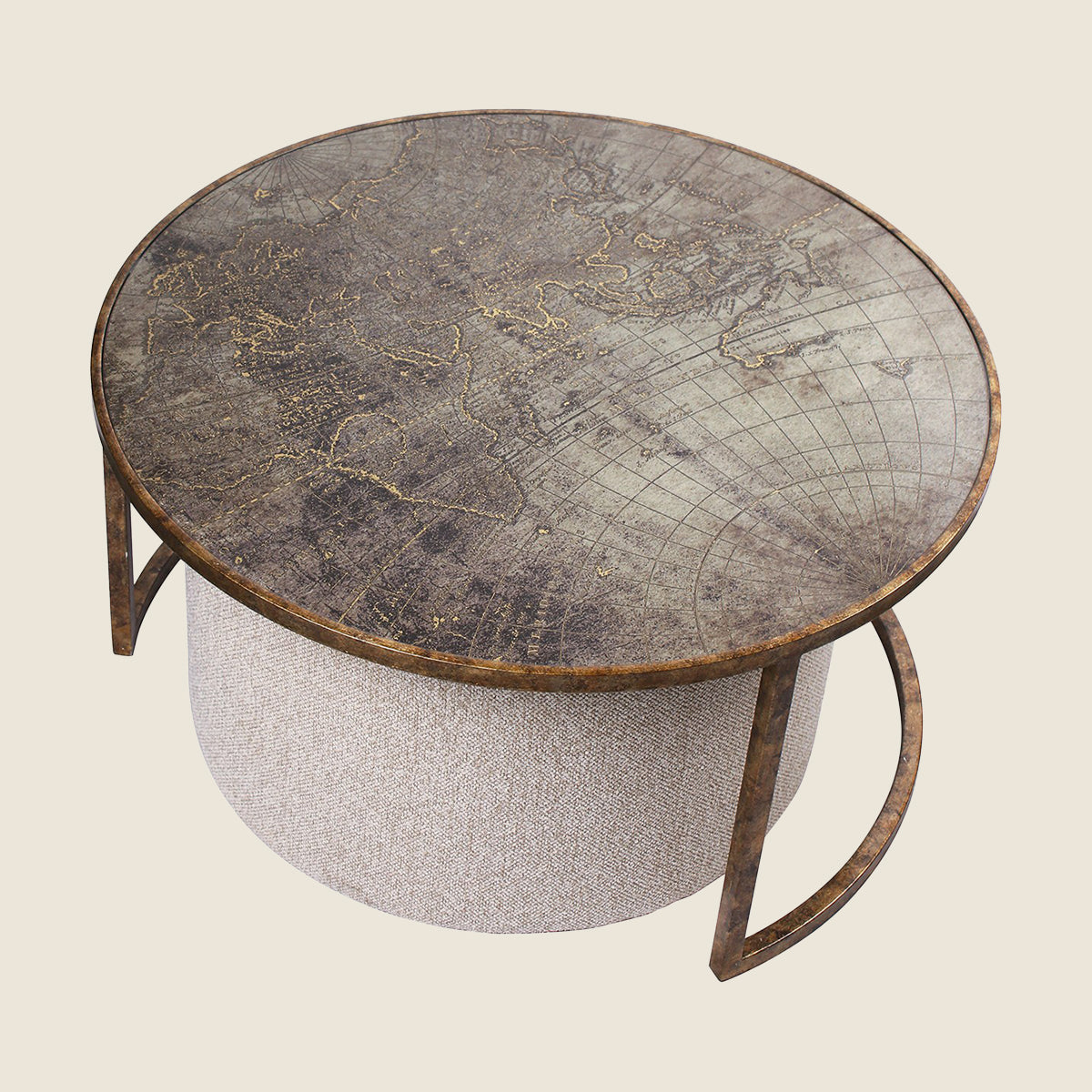 Round coffee table with an antique-style world map print on the top, supported by a cylindrical textured cream ottoman and curved metal legs, shown on a solid light beige background.