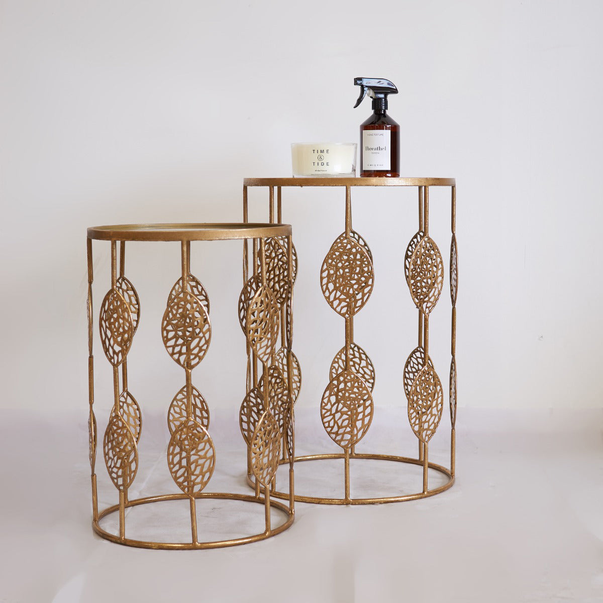 Two gold metal side tables with decorative patterns on a white background