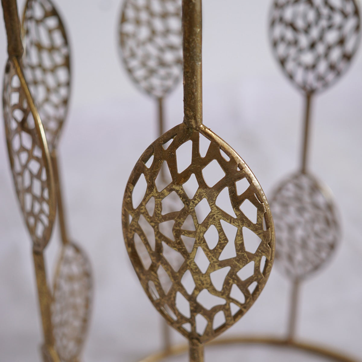 Decorative metal side tables with leaf-like patterns on a plain background
