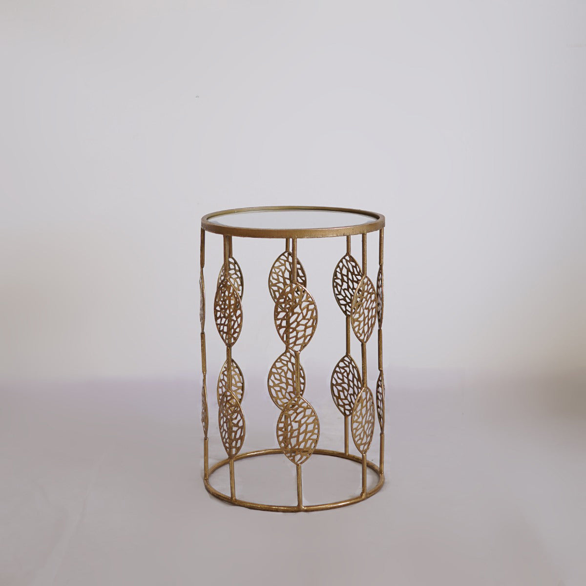 Decorative gold side table with intricate leaf patterns on a light gray background