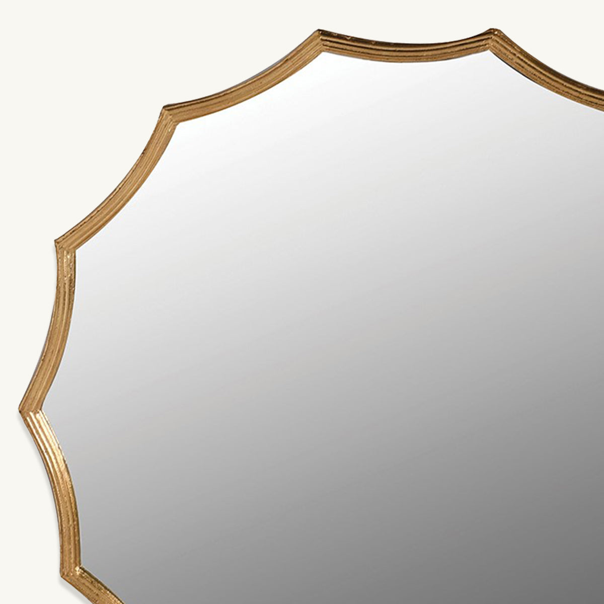 A close up of a gold scalloped edge wall mirror.