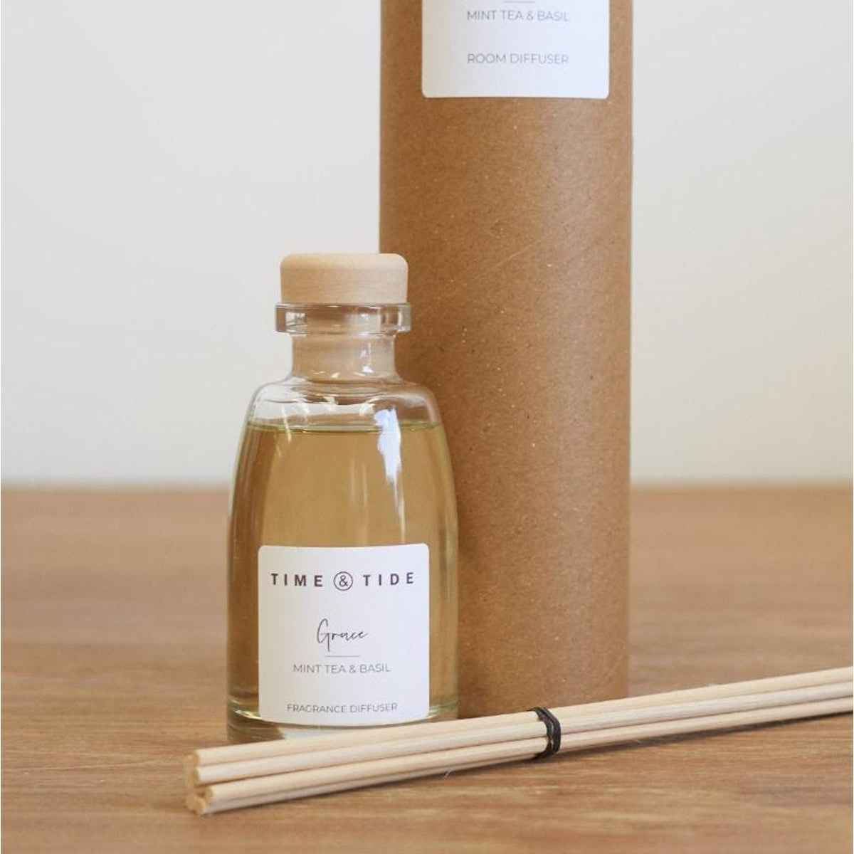 Bottle of 'Grace' room diffuser by Time & Tide with reeds on a wooden surface.