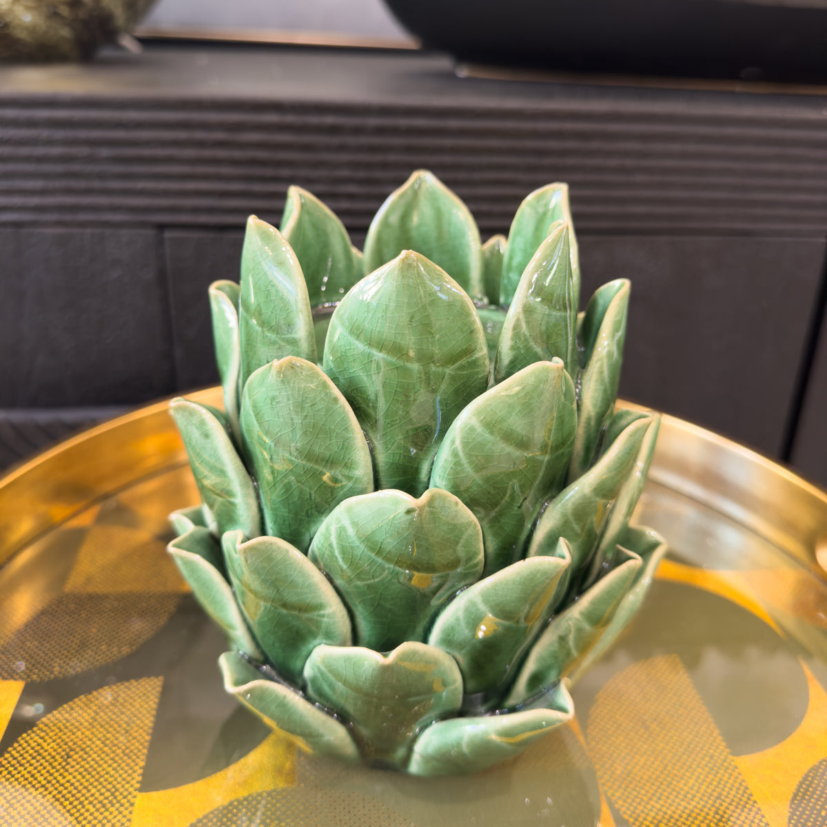 Green artichoke decoration on a decorative tray with a blurred background