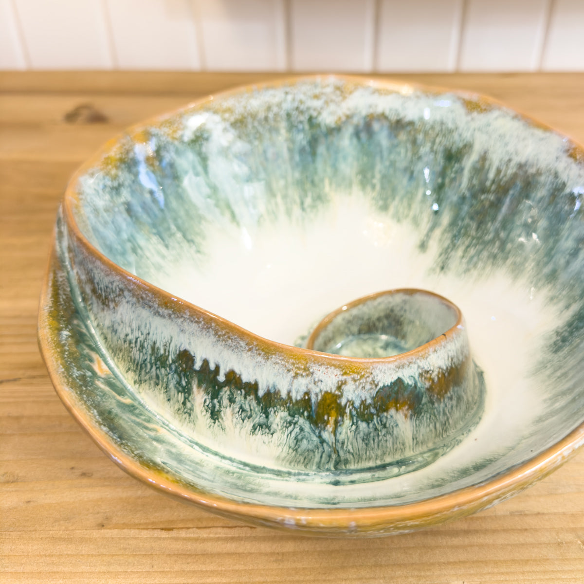 Ceramic bowl with green and brown glaze on a wooden surface