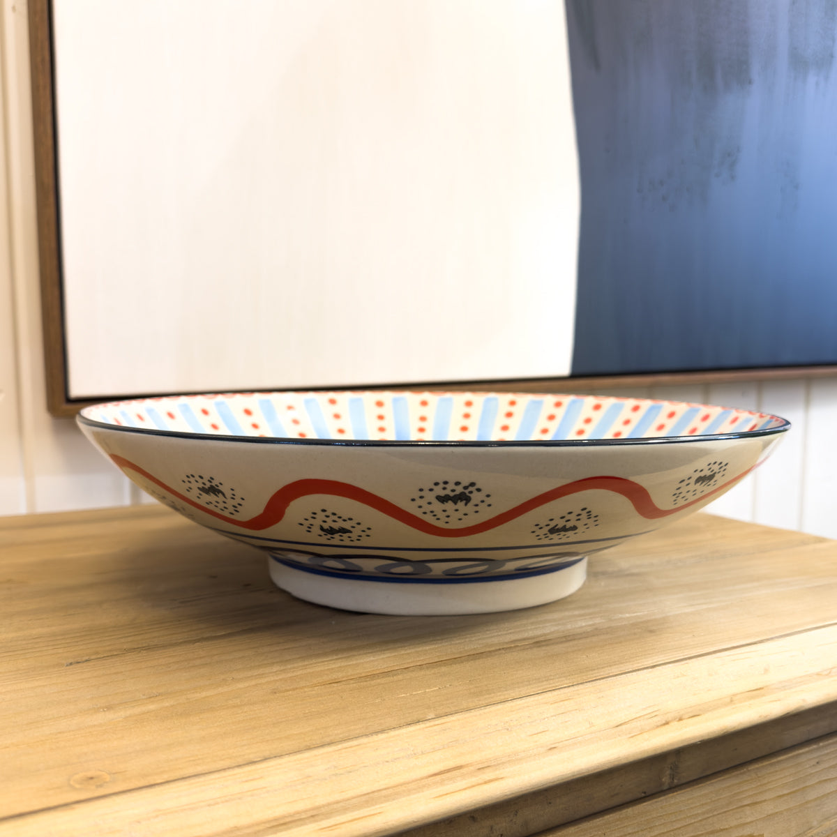 Decorative ceramic bowl with wavy pattern on a wooden surface