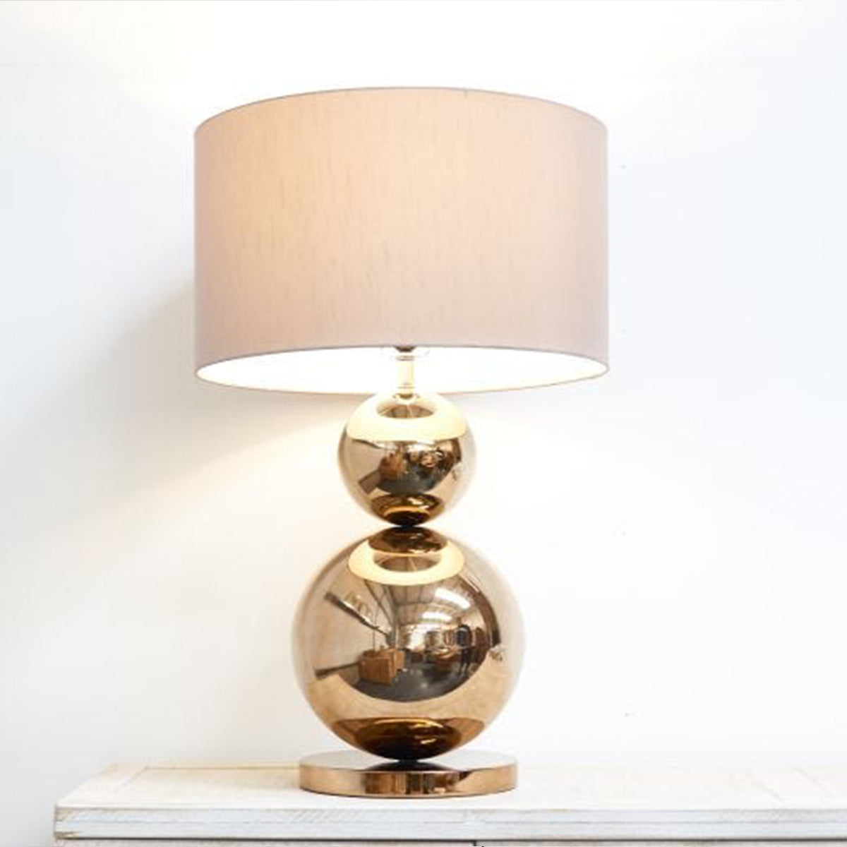 A table lamp with a bronze ball base, and a beige neutral shade.