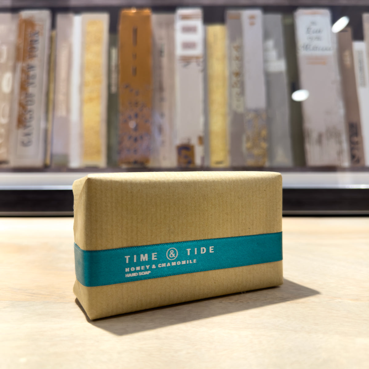 Bar of soap with 'Time & Tide' label on a wooden surface, books in the background