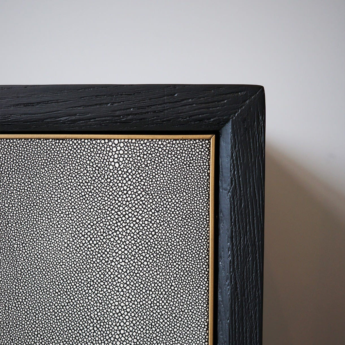 Close-up of a textured black sideboard corner with a light gray background