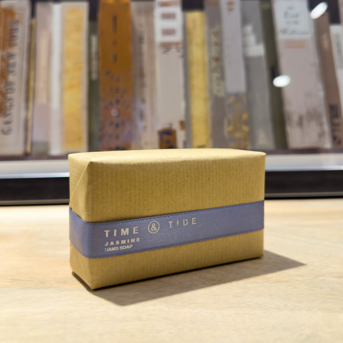 Jasmine soap bar with a grey label on a wooden surface, with books in the background.