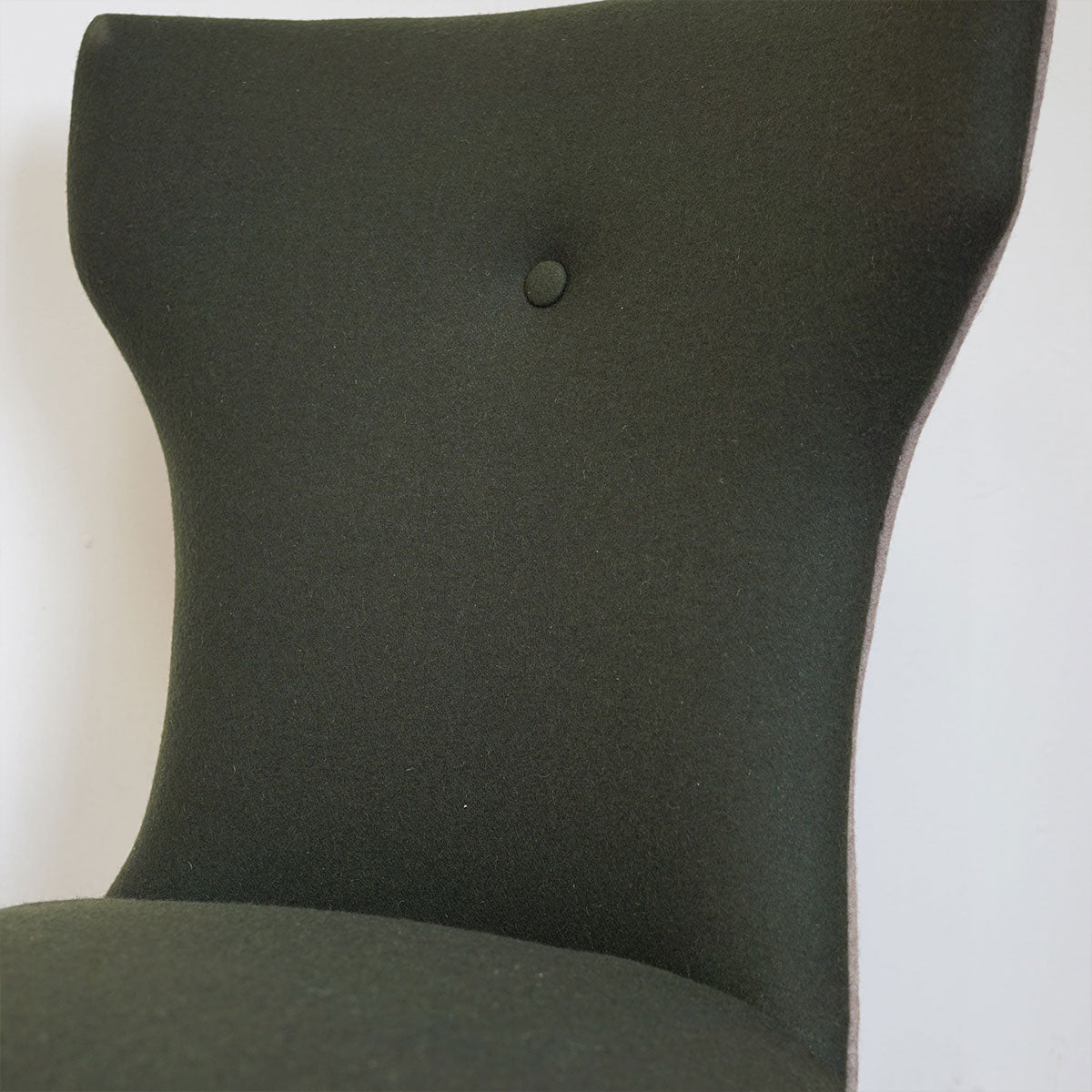 Dark green felt dining chair with a button on a white background