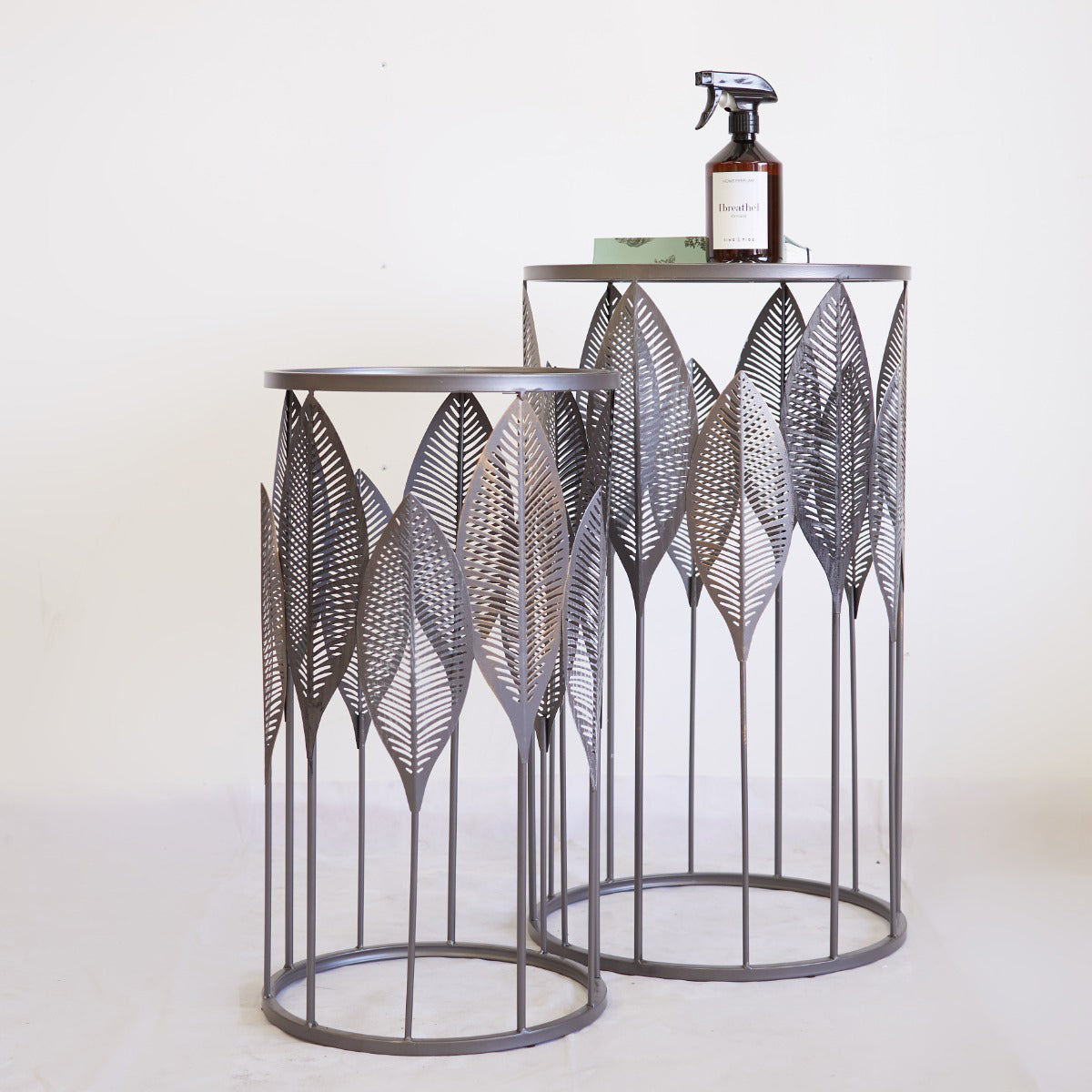 Two decorative metal side tables with leaf patterns on a white background