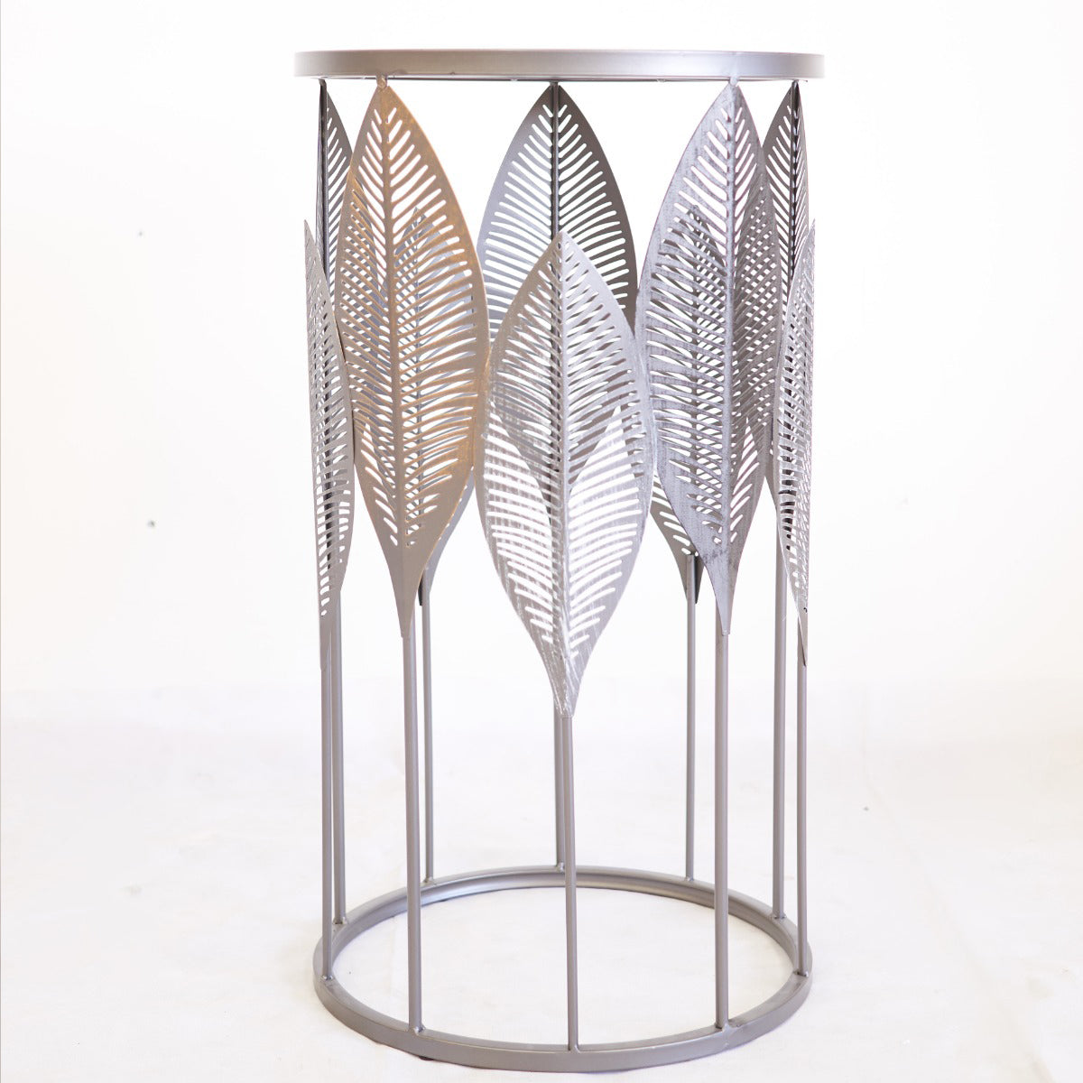 Decorative metal side table with leaf patterns on a white background